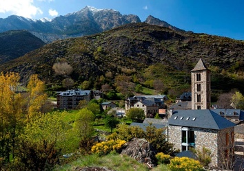 Romanische Kirche Sant Joan im Dorf Boí im Vall de Boí, UNESCO-Welterbe, umgeben von steinernen Pyrenäenhäusern